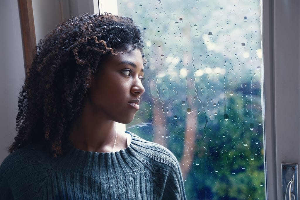 woman looking depressed out rainy window