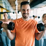happy man lifting weights having fun at gym
