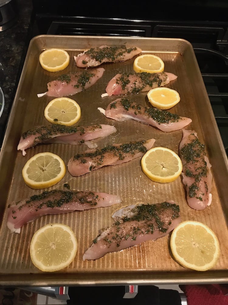 Greek chicken and lemon slices layered in sheet pan